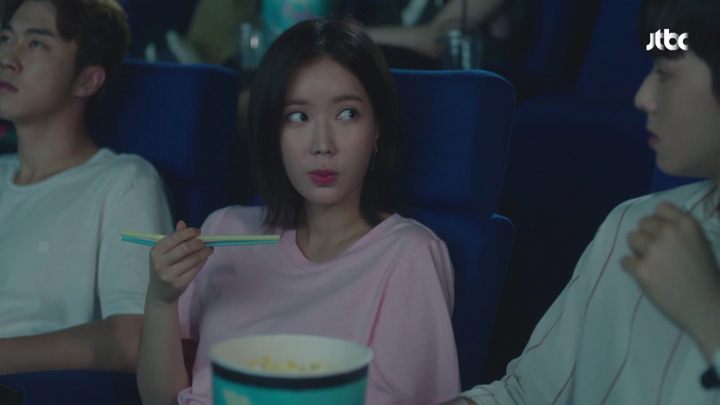 Kang Mi Rae using straws as chopsticks to grab her popcorn.
